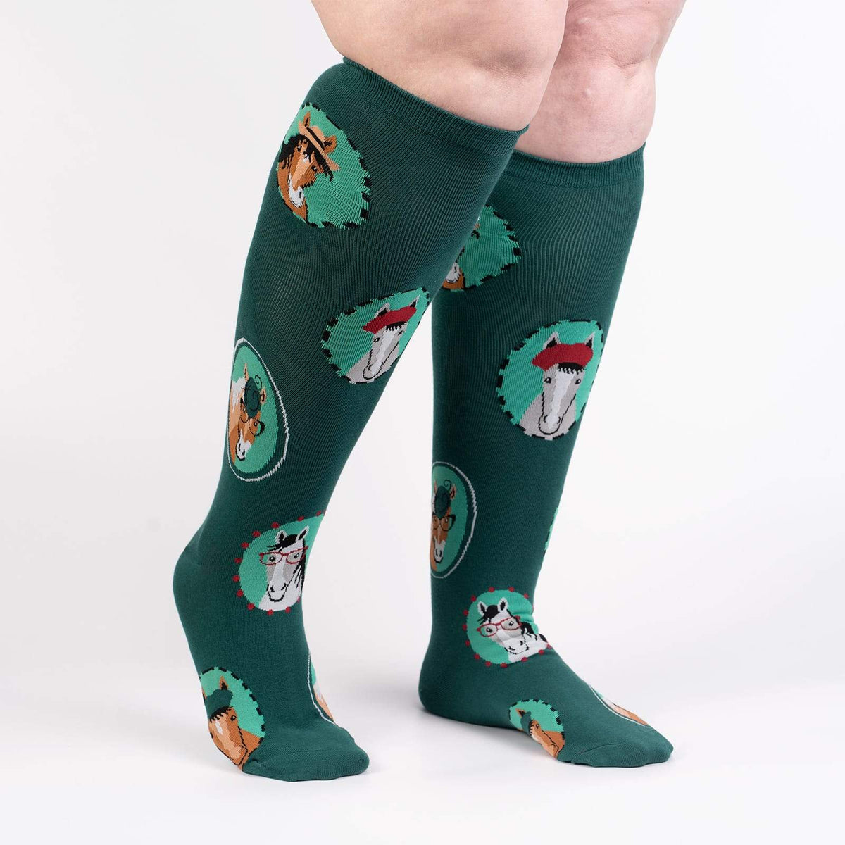 Sock It To Me Horsing Around extra-stretchy women&#39;s and men&#39;s knee high socks featuring teal socks with pictures of horses wearing hats and/or glasses. Socks shown on model from side. 