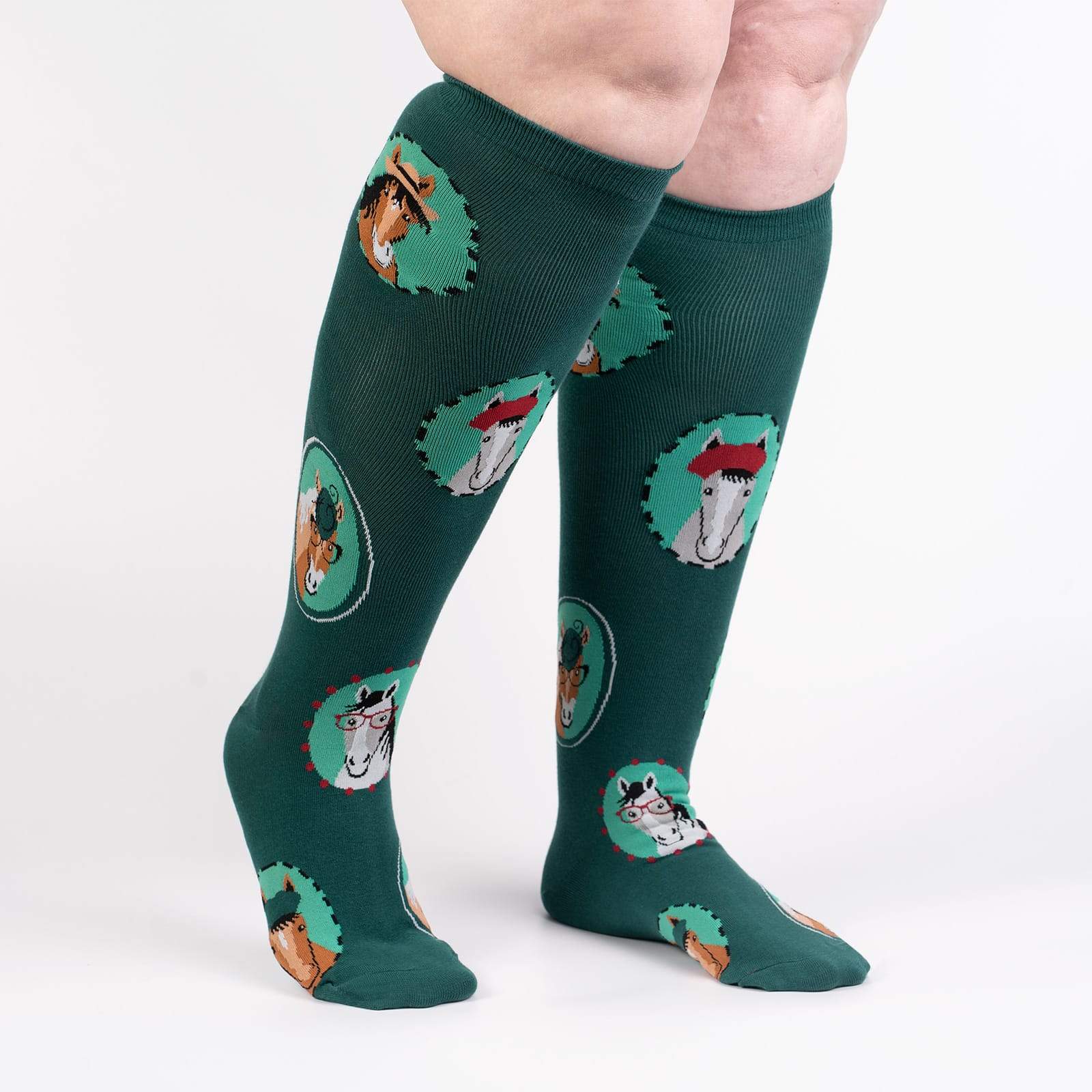Sock It To Me Horsing Around extra-stretchy women's and men's knee high socks featuring teal socks with pictures of horses wearing hats and/or glasses. Socks shown on model from side. 