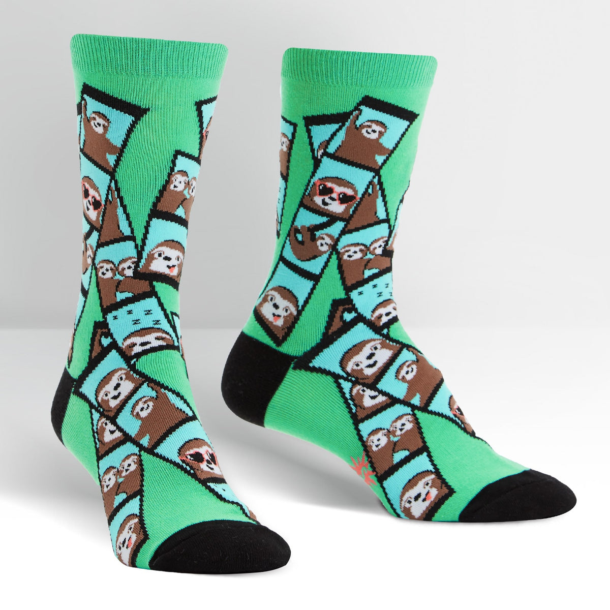 Sock It To Me Oh Snap! women&#39;s crew sock. Featuring green sock with photo booth images of sloths all over. Socks shown on display feet. 