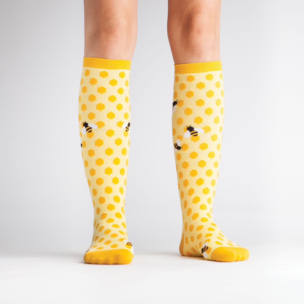 Sock It To Me women&#39;s knee high sock Bees KneesSock It To Me women&#39;s yellow knee high sock Bees Knees featuring honeycomb and bees all over on model from front
