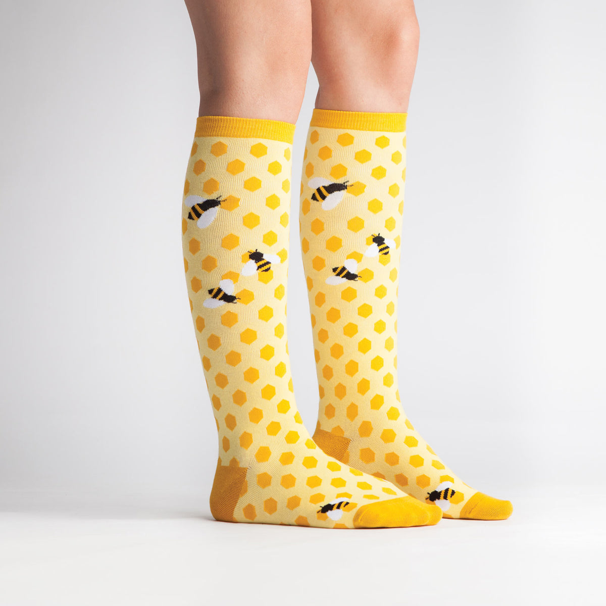 Sock It To Me women&#39;s yellow knee high sock Bees Knees featuring honeycomb and bees all over on model from side
