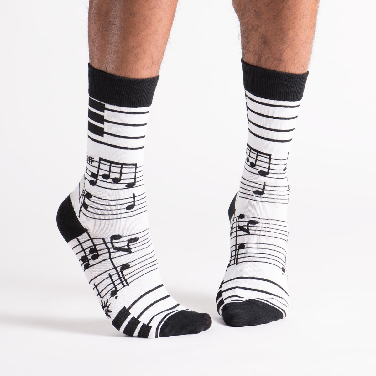 Sock it to Me Foot Notes men&#39;s crew high sock featuring white sock with black musical notes all over on model from front