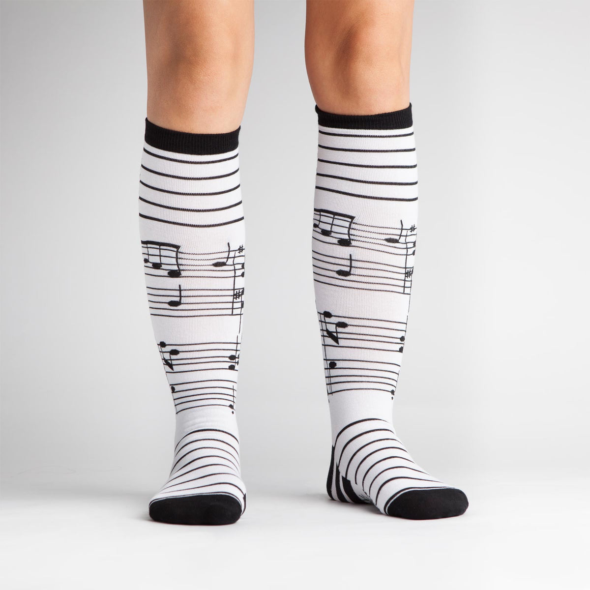 Sock it to Me Foot Notes women&#39;s knee high sock featuring white sock with black musical notes all over on model from front