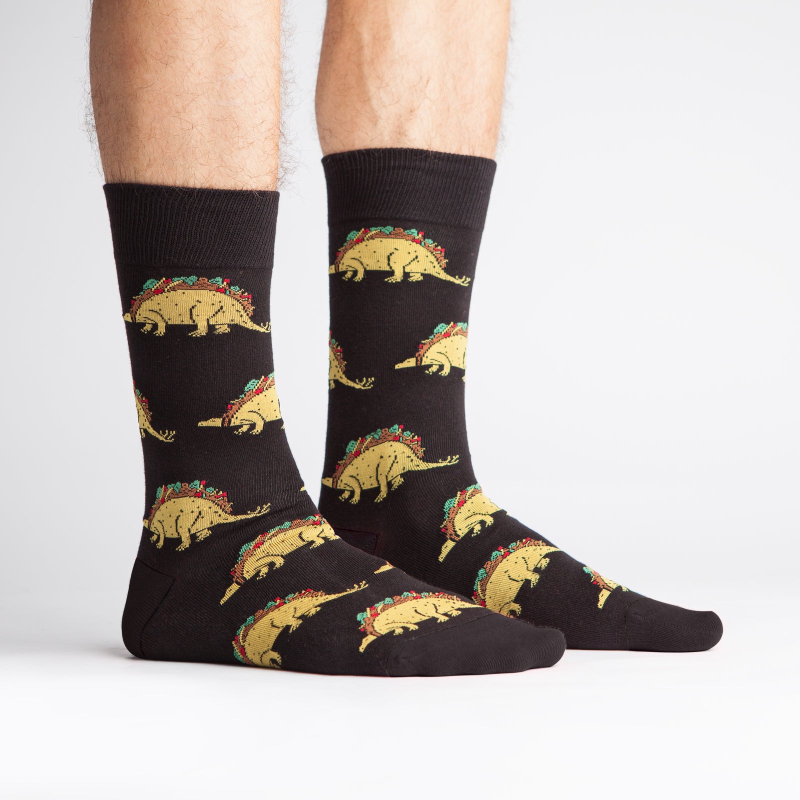 Sock It To Me black men's crew sock Tacosaurus featuring taco-dinosaurs all over worn by model seen from side